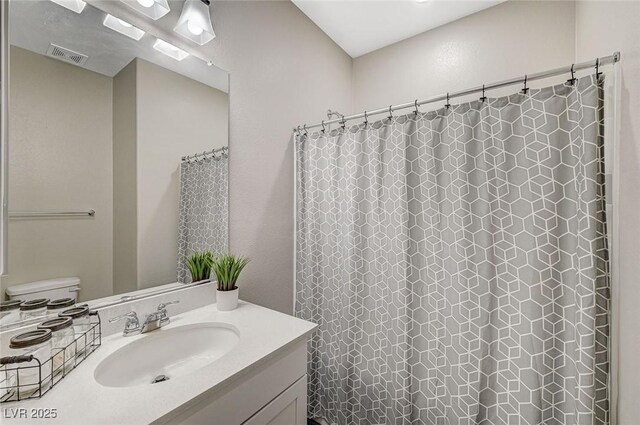 bathroom with vanity, curtained shower, toilet, and visible vents