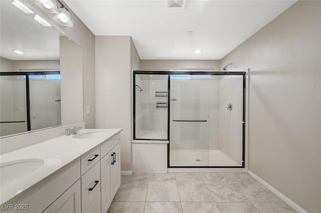full bathroom featuring visible vents, a shower stall, baseboards, double vanity, and a sink