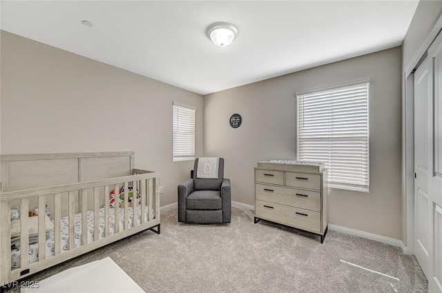 carpeted bedroom featuring a closet, baseboards, and a nursery area