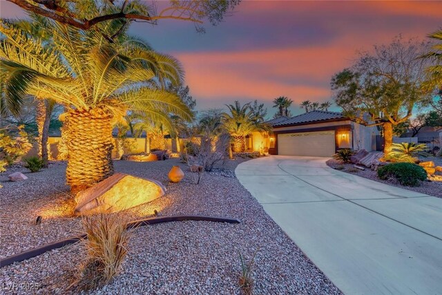 view of front of property featuring a tile roof, stucco siding, concrete driveway, and a garage