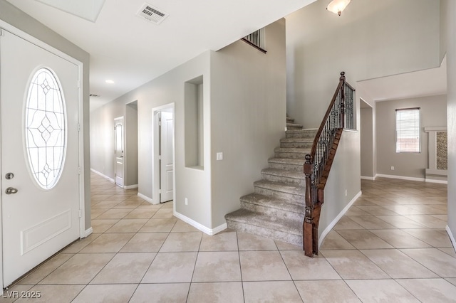 entrance foyer with light tile patterned floors, stairs, and baseboards