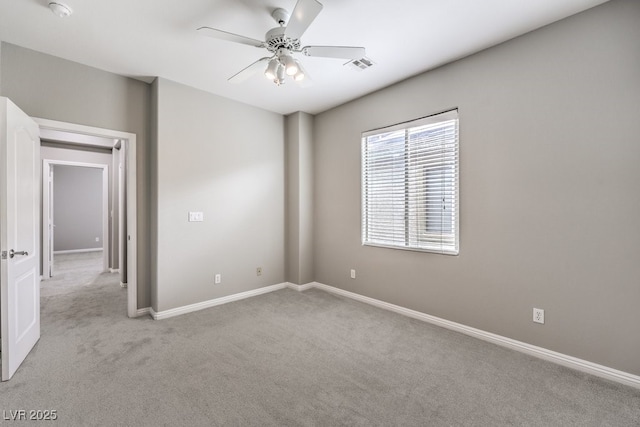 empty room featuring light colored carpet, a ceiling fan, baseboards, and a smoke detector