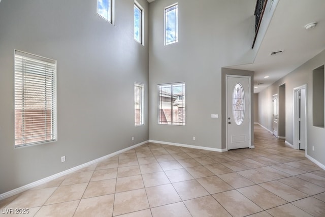 foyer entrance with light tile patterned floors, plenty of natural light, a towering ceiling, and baseboards