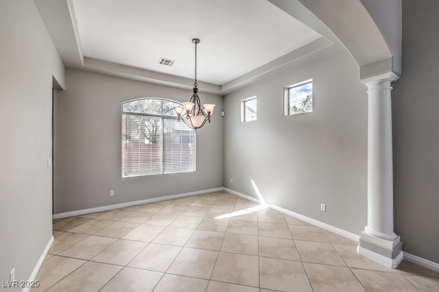 unfurnished room featuring a tray ceiling, light tile patterned floors, decorative columns, a chandelier, and baseboards