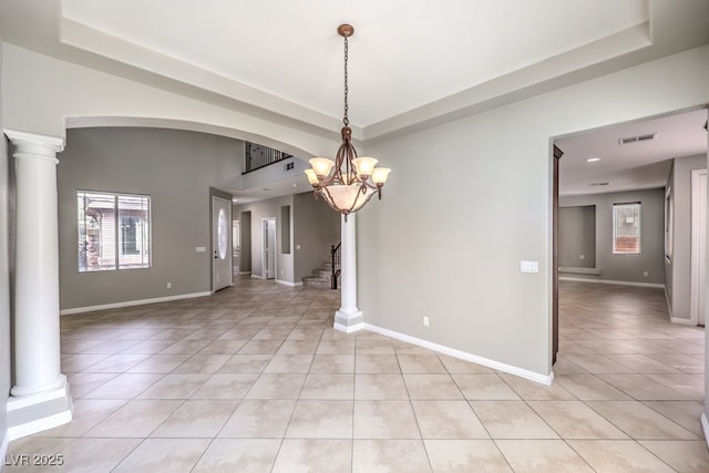 unfurnished room featuring a tray ceiling, light tile patterned flooring, a chandelier, and plenty of natural light