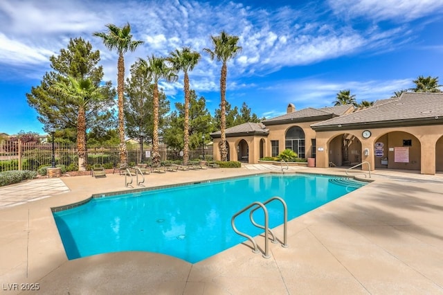 community pool with a patio area and fence