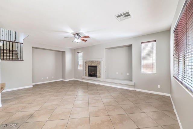 unfurnished living room with a ceiling fan, plenty of natural light, and baseboards