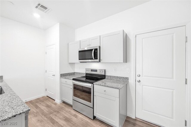 4125 Venus Falls Ave, North Las Vegas, NV 89084 - kitchen with appliances with stainless steel finishes, light wood finished floors, light stone counters, and white cabinetry