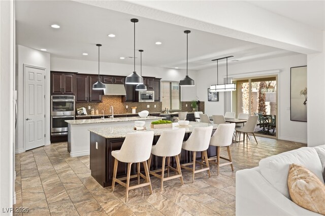 50 Carolina Cherry Dr, Las Vegas, NV 89141 - kitchen featuring a spacious island, stainless steel appliances, under cabinet range hood, plenty of natural light, and recessed lighting