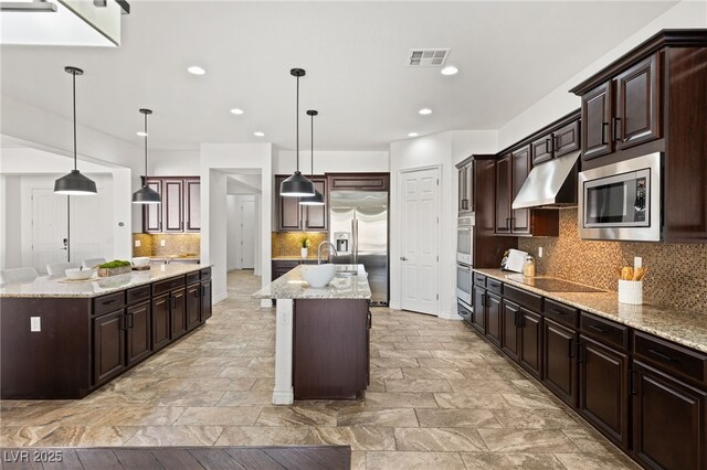 50 Carolina Cherry Dr, Las Vegas, NV 89141 - kitchen with a center island with sink, under cabinet range hood, built in appliances, tasteful backsplash, and recessed lighting