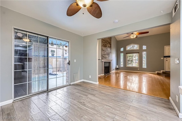 unfurnished living room featuring a fireplace, wood finished floors, visible vents, and ceiling fan