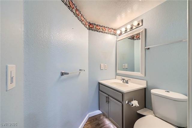 bathroom featuring baseboards, toilet, wood finished floors, and vanity