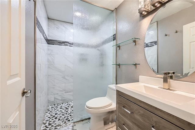 bathroom with toilet, marble finish floor, vanity, and a tile shower
