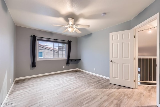 empty room featuring light wood-style flooring, baseboards, and ceiling fan
