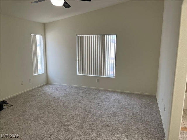 carpeted spare room featuring baseboards and ceiling fan