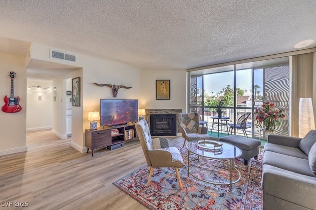 725 N Royal Crest Cir Unit 227, Las Vegas, NV 89169 - living room with baseboards, a fireplace, light wood-style floors, a textured ceiling, and floor to ceiling windows