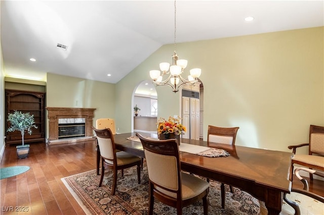 380 Claremont St, Boulder City, NV 89005 - dining space with lofted ceiling, a high end fireplace, visible vents, a chandelier, and dark wood-style flooring