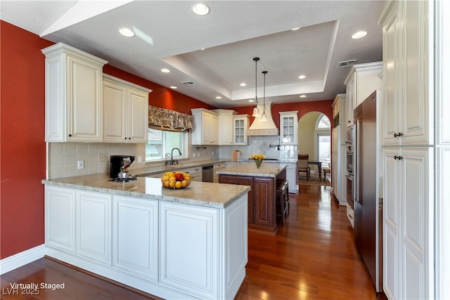 380 Claremont St, Boulder City, NV 89005 - kitchen with tasteful backsplash, arched walkways, a raised ceiling, a peninsula, and dark wood-style floors