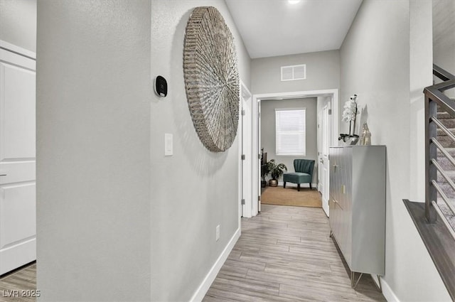 hallway featuring visible vents, baseboards, and light wood-style flooring