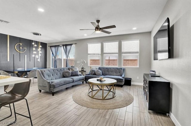 living room with light wood-style floors, baseboards, a ceiling fan, and visible vents