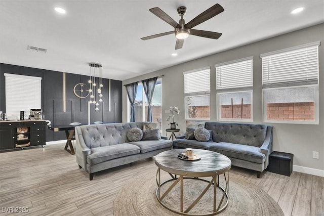 living room featuring ceiling fan, visible vents, recessed lighting, light wood finished floors, and baseboards