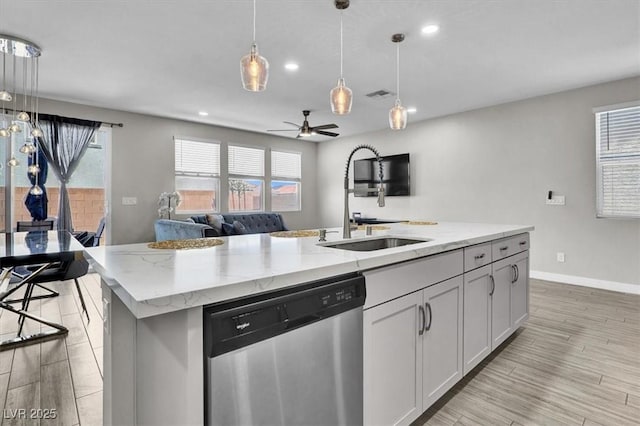 kitchen with visible vents, dishwasher, a sink, open floor plan, and light stone counters
