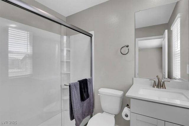 bathroom featuring toilet, a wealth of natural light, a stall shower, and vanity