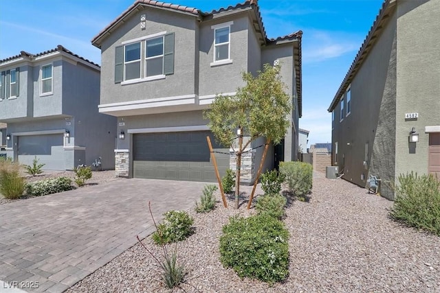 view of front of home with cooling unit, stucco siding, a tile roof, an attached garage, and driveway