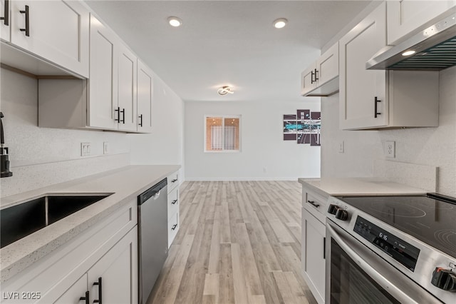 2915 Cedar Ave Unit 12C, Las Vegas, NV 89101 - kitchen featuring under cabinet range hood, a sink, white cabinetry, stainless steel appliances, and light wood-style floors