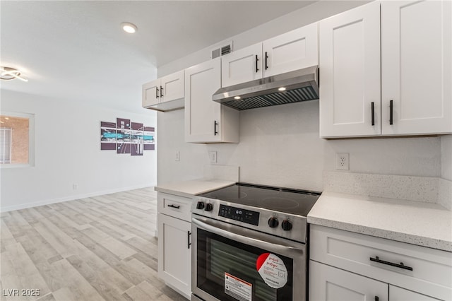 2915 Cedar Ave Unit 12C, Las Vegas, NV 89101 - kitchen featuring visible vents, stainless steel range with electric stovetop, light wood-style flooring, under cabinet range hood, and white cabinets