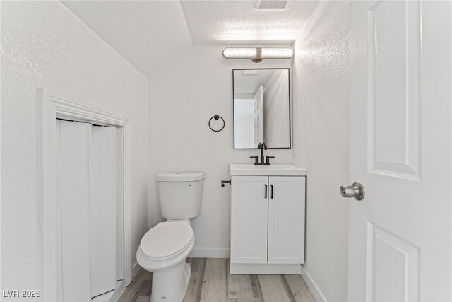 2915 Cedar Ave Unit 12C, Las Vegas, NV 89101 - bathroom featuring vanity, wood finished floors, vaulted ceiling, a textured ceiling, and toilet