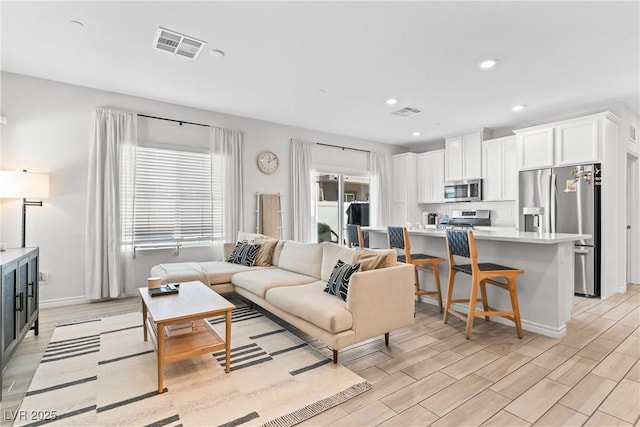 living area with recessed lighting, light wood-type flooring, and baseboards