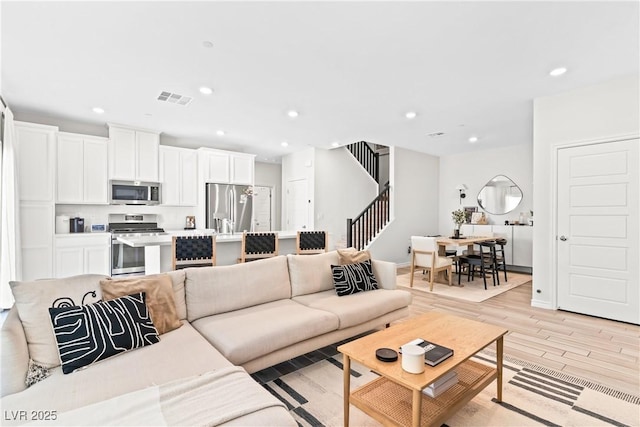 living room with stairs, recessed lighting, light wood-type flooring, and baseboards