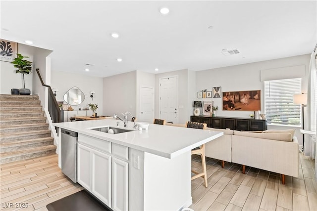 kitchen featuring a sink, stainless steel dishwasher, open floor plan, wood finish floors, and recessed lighting