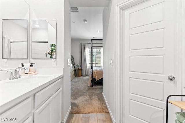 bathroom with wood finished floors, vanity, and ensuite bath