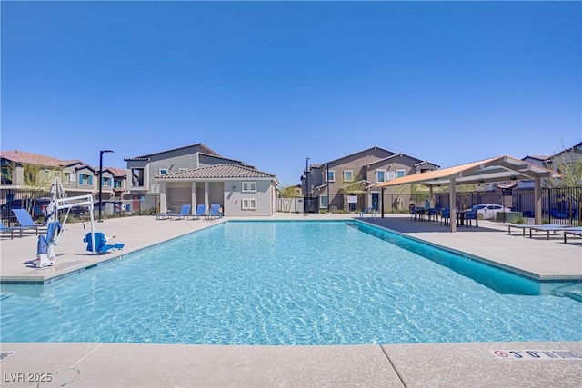 community pool with a residential view, fence, and a patio