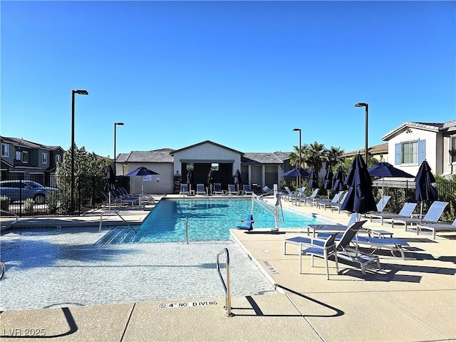 community pool with fence, a patio area, and a residential view