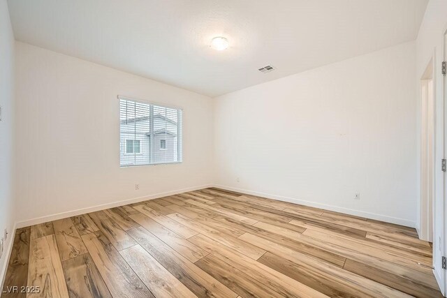 spare room with light wood finished floors, baseboards, and visible vents