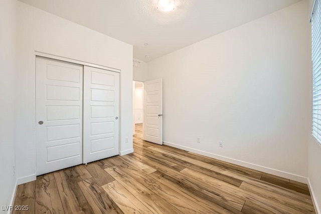 unfurnished bedroom featuring baseboards, a closet, and wood finished floors