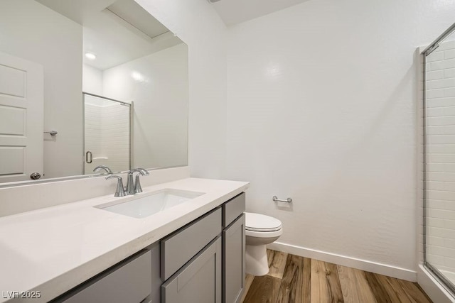 bathroom featuring a stall shower, baseboards, toilet, vanity, and wood finished floors
