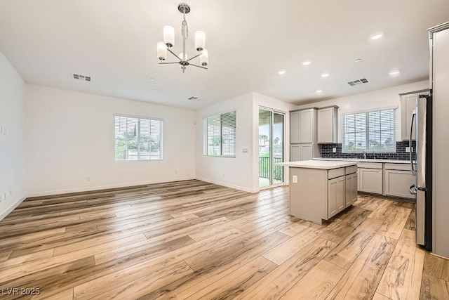 kitchen with freestanding refrigerator, gray cabinets, light wood finished floors, and visible vents