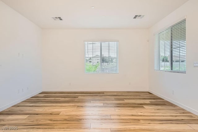 unfurnished room with a healthy amount of sunlight, light wood-style flooring, and visible vents