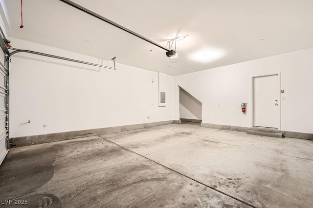 garage featuring baseboards, electric panel, and a garage door opener