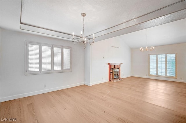 2916 W Oakey Blvd, Las Vegas, NV 89102 - empty room featuring a chandelier, light wood-style floors, lofted ceiling, baseboards, and a brick fireplace