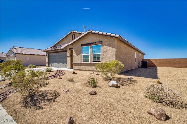 view of front of home featuring an attached garage, central AC, stucco siding, concrete driveway, and a tiled roof