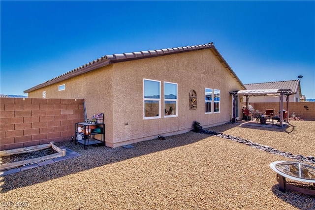 back of house featuring a patio, fence, a pergola, stucco siding, and a fire pit