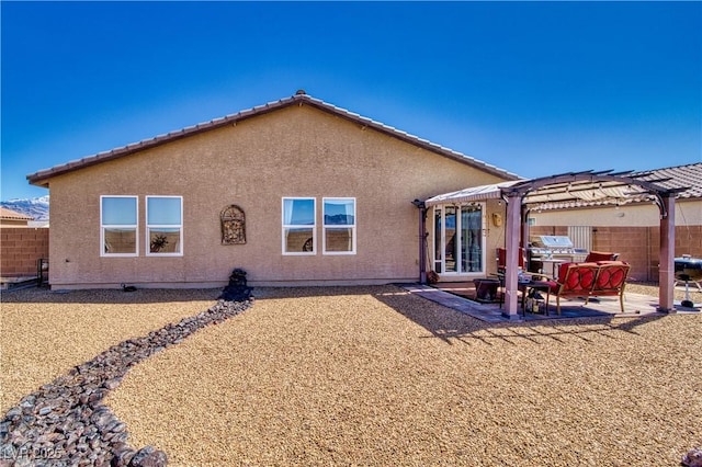 back of house with stucco siding, a pergola, a patio, and fence