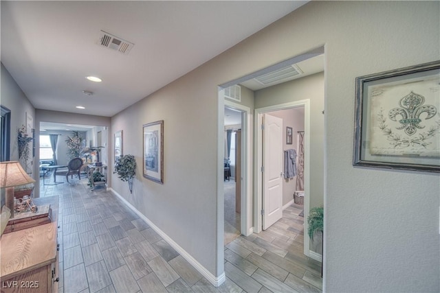 hallway with visible vents, baseboards, and wood tiled floor