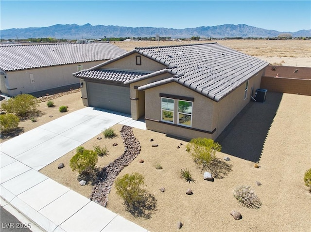 view of front facade featuring a tile roof, concrete driveway, stucco siding, a garage, and a mountain view