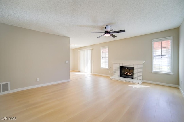 6649 W Tropicana Ave Unit 101, Las Vegas, NV 89103 - unfurnished living room with a ceiling fan, a fireplace, light wood-style floors, a textured ceiling, and baseboards